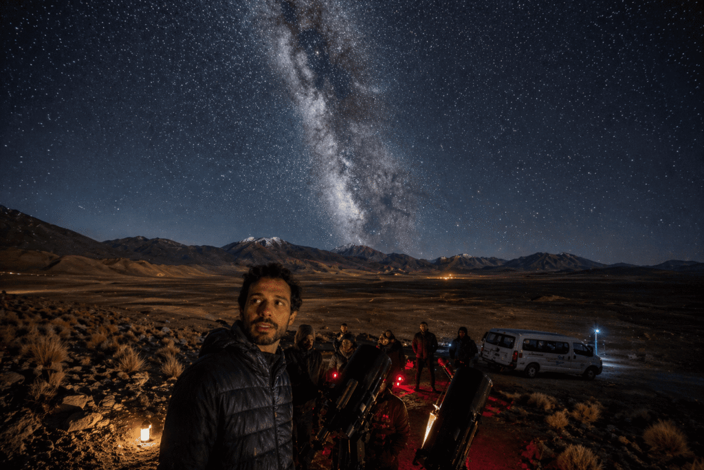 Céu estrelado com a Via Láctea visível sobre telescópios profissionais no Deserto do Atacama. Imagem de tour astronómico guiado para brasileiros com astrofotografia.